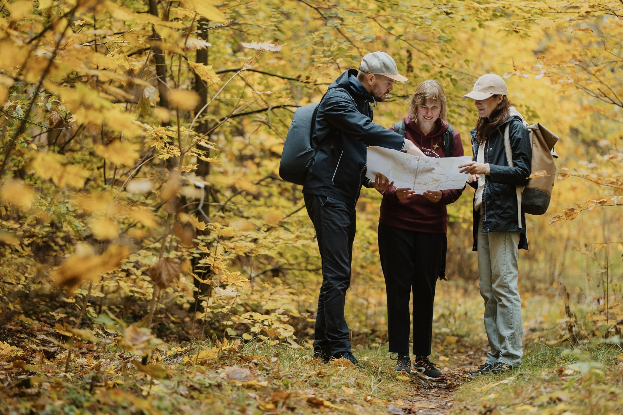 Trys VU Karjeros konsultantai studijuoja žėmėlapį miške