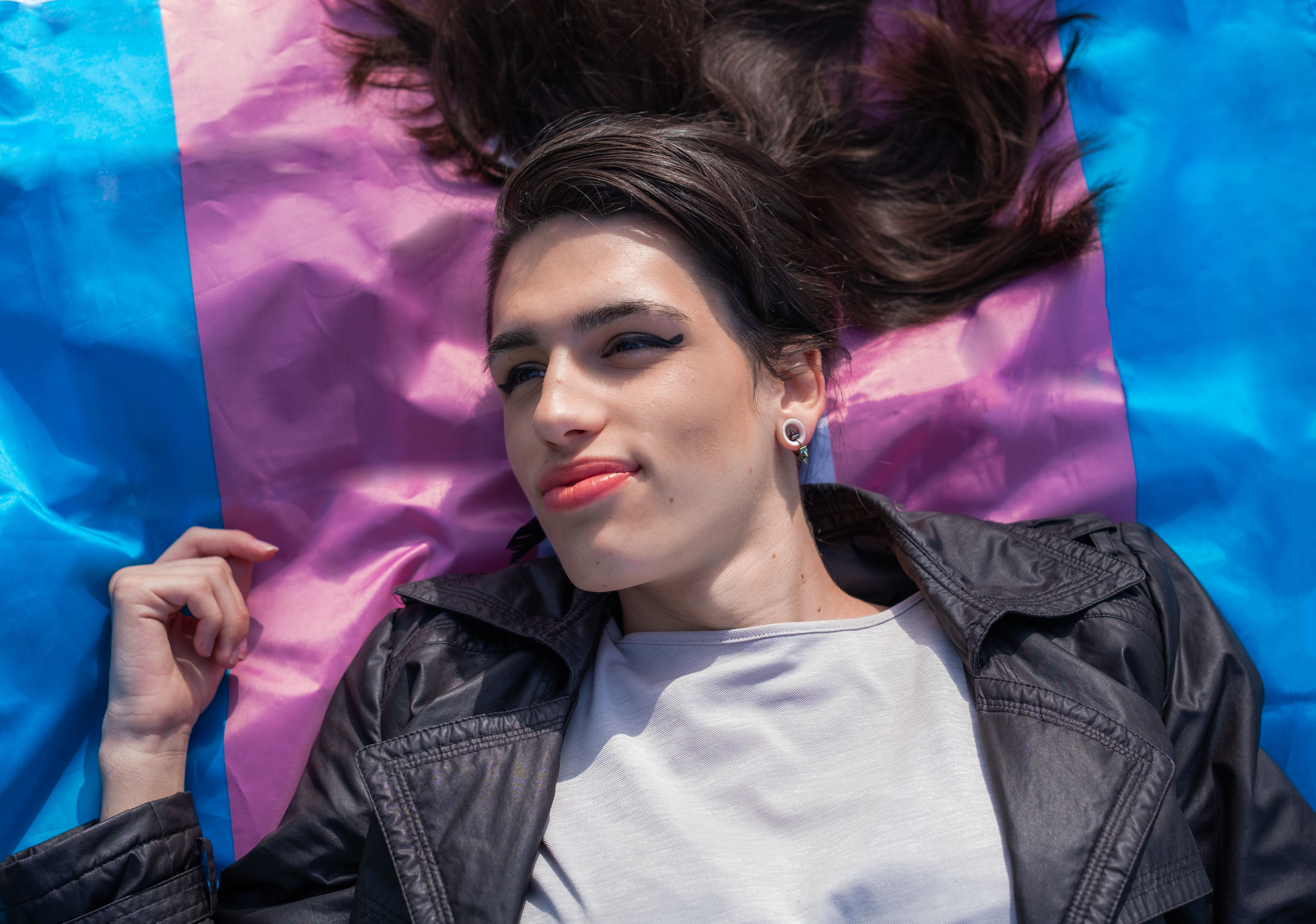 Overhead shot of a transsexual woman lying on the multicolored trans flag. We activate LGTBIQ+