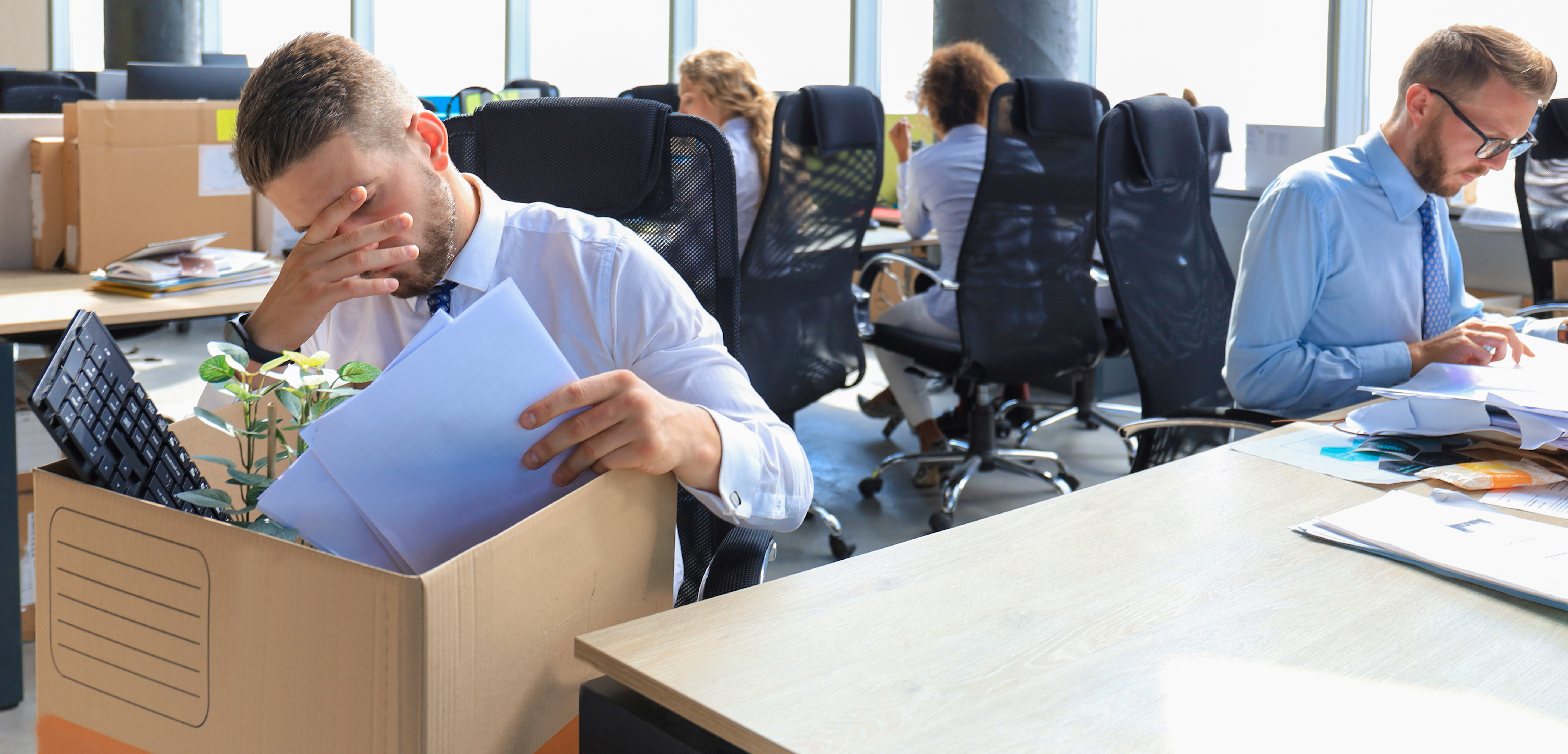 Sad dismissed worker are taking his office supplies with him from office.